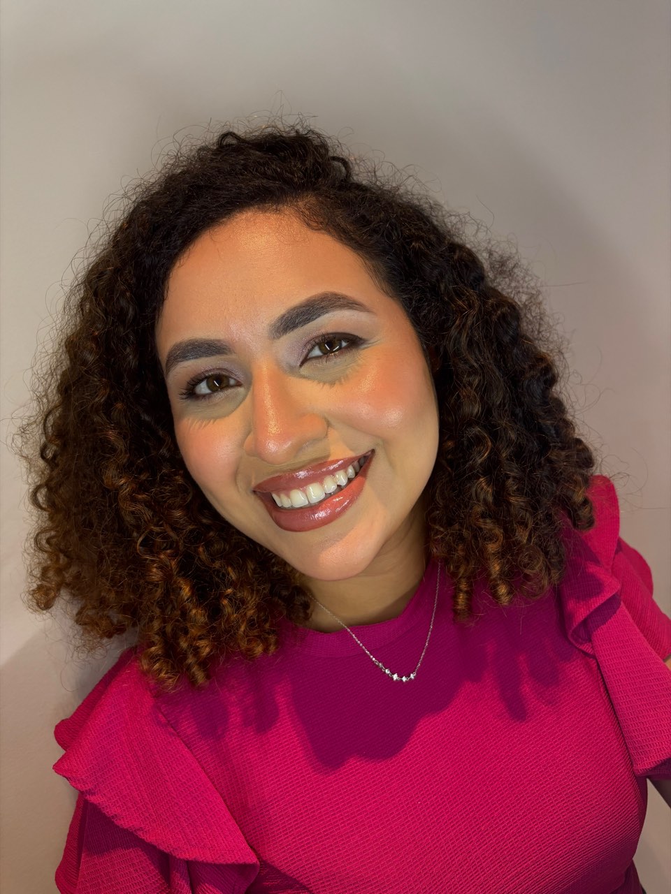 Cliente de cabelo cacheado com pele iluminada e boca em tom rosado.
